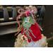 This shows the Christmas arrangement on top of the elf hat. It includes pine sprigs, a reindeer ornament, red berries, and a faux candy.